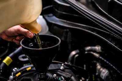 adding oil to car during oil change service