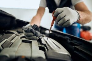 auto mechanic checking a car's engine oil level